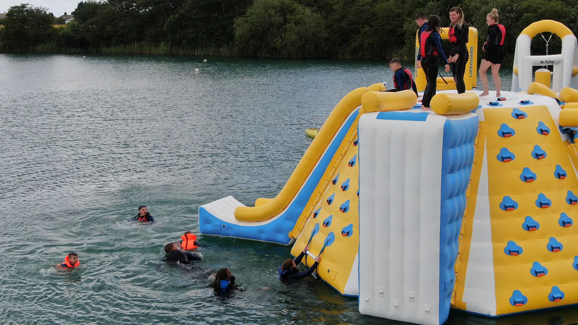 People in the water by the side of the inflatable high jump